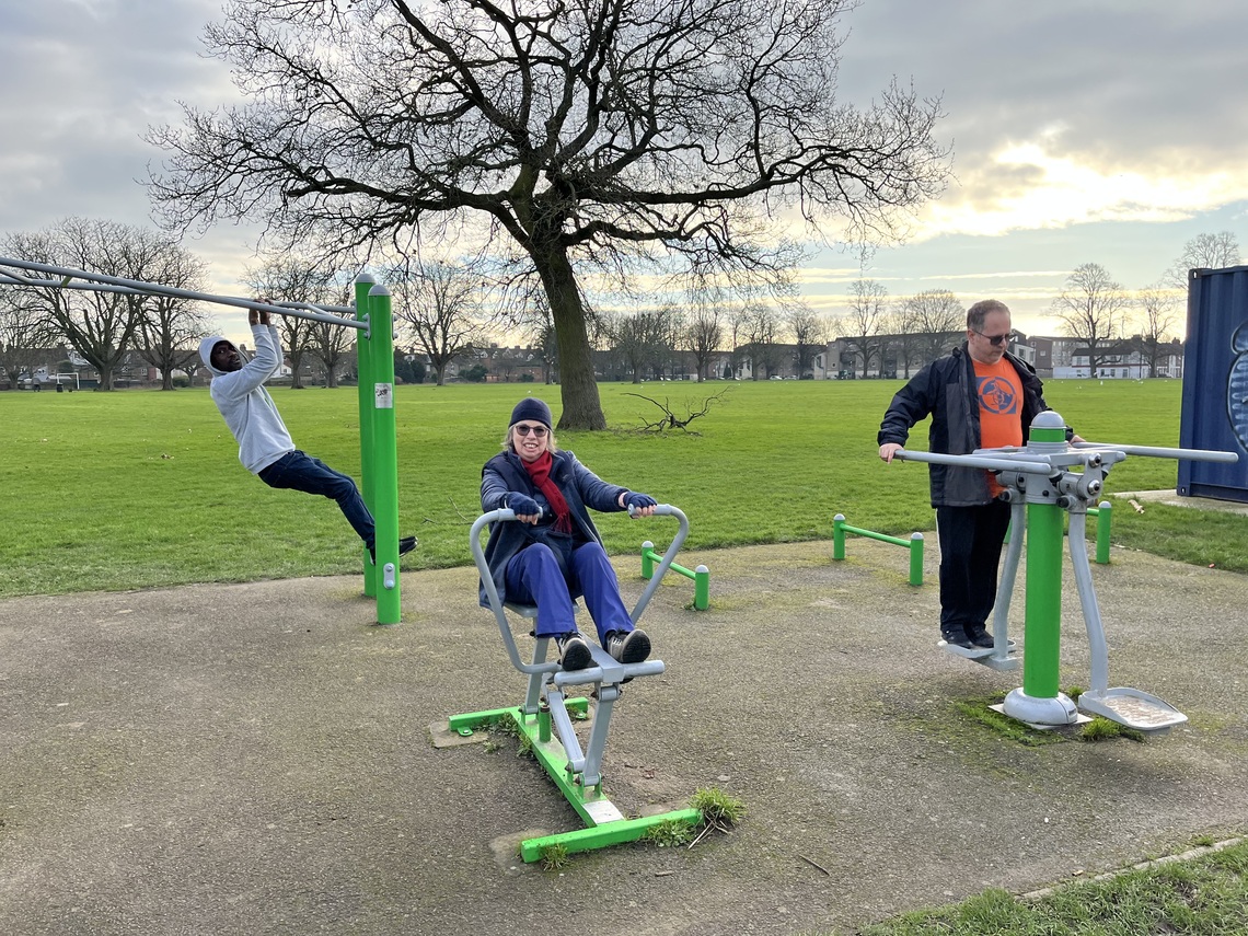 Three Adults trying out different outdoor gym equipment